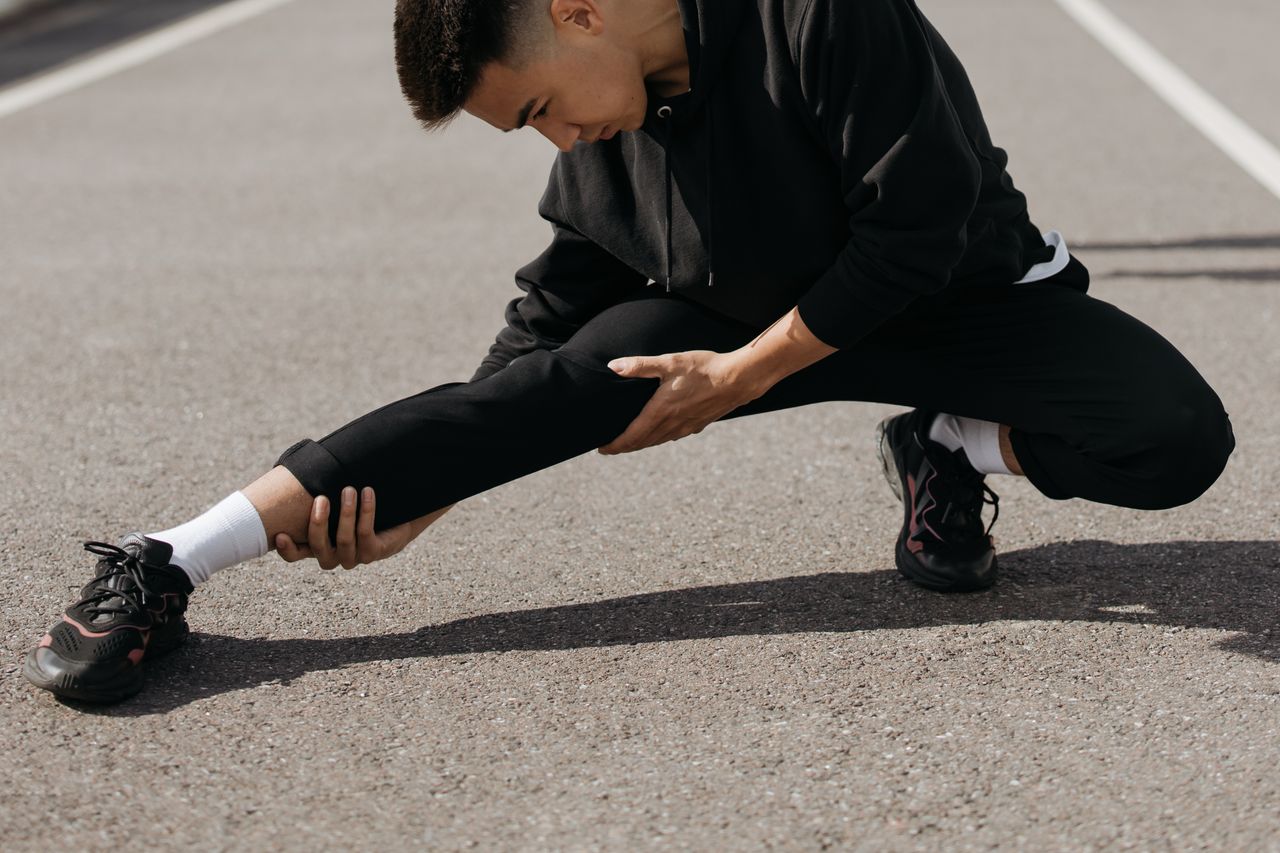 The Art of Drawing Readers In: Your attractive post title goes here A young man performs stretching exercises on a city street, focusing on flexibility and fitness.