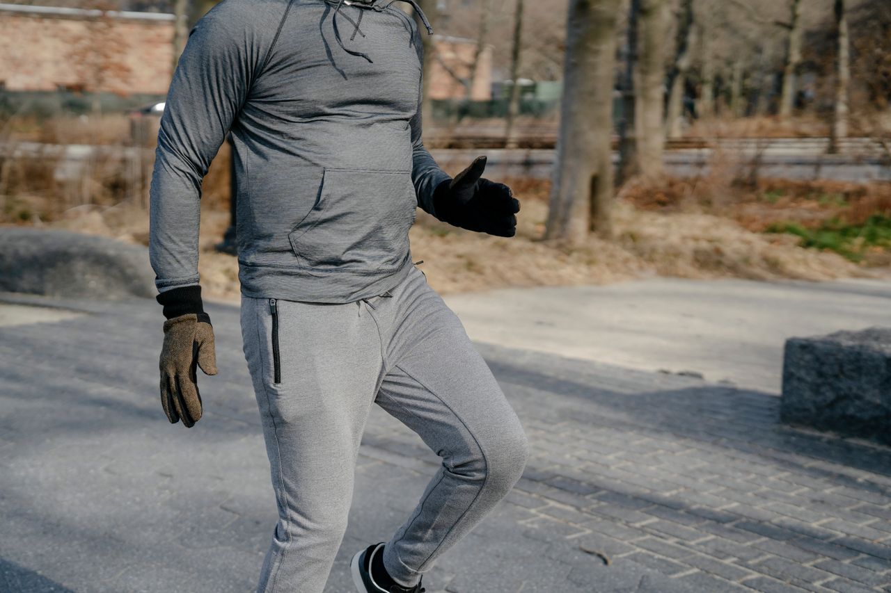 about-img-01 Crop anonymous male in sportswear and gloves jumping on one leg while warming up before workout training in city park